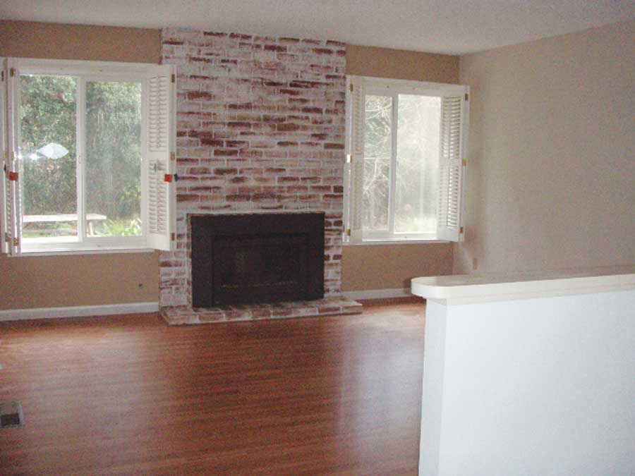 Carol's pre-remodel living room had laminate flooring, beige walls and badly painted fireplace bricks.